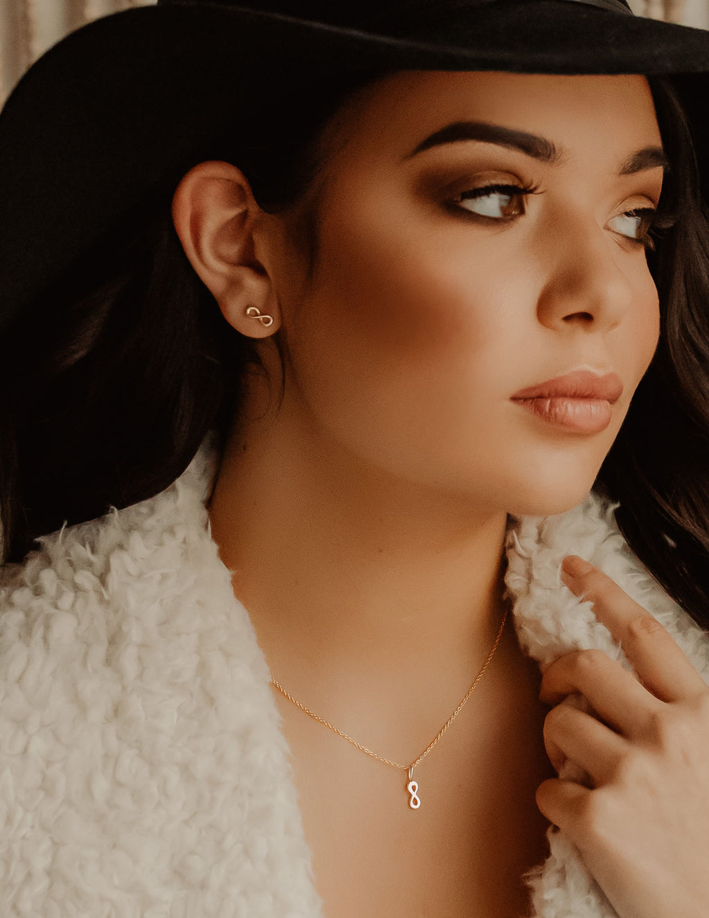 Woman glancing to the side with infinity necklace and earrings on