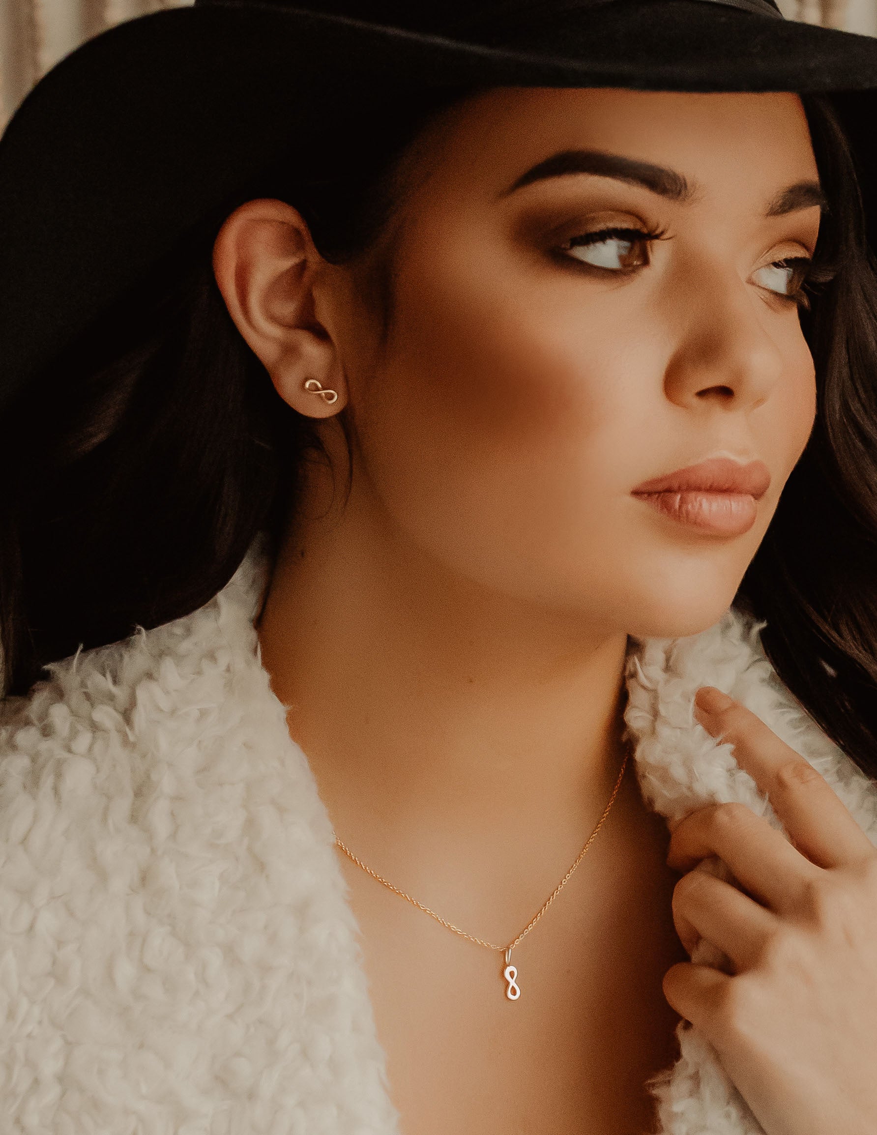 Woman glancing to the side with infinity necklace and earrings on