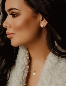 Woman side profile wearing gold bison necklace and earrings