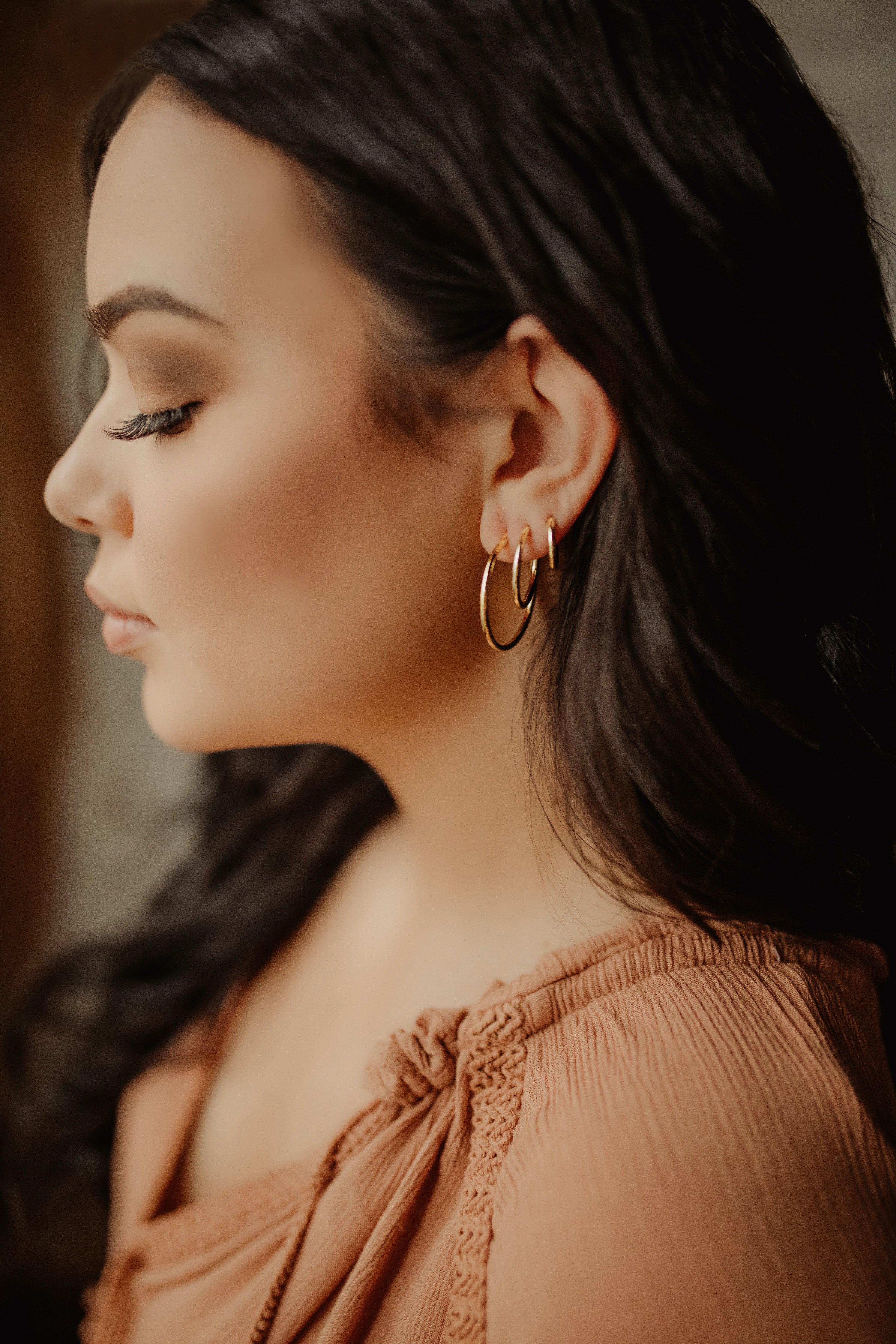 Woman facing sideways wearing medium hoop earrings and other sized hoops