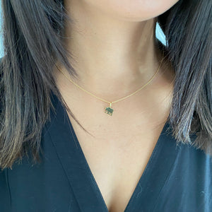 Woman's neck wearing gold bear necklace.
